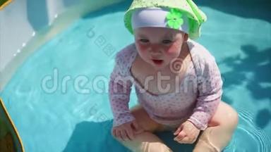 一个在游泳池里的小而有趣的婴儿用双手捂住脸